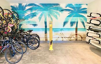 A group of bikes parked in front of a wall mural of a beach with palm